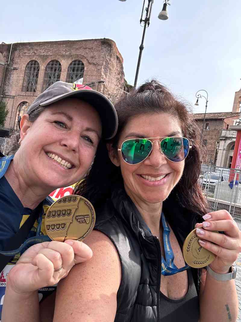 Ellen Himelfarb, right, and a fellow “fitwalker” with their Run Rome medals